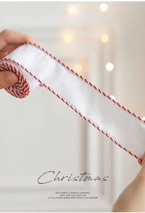 Close-up of white satin Christmas ribbon with red and silver twisted rope edges