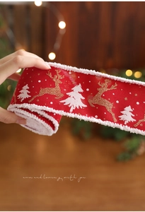 Detail der roten Weihnachtsschleife mit weißem Plüschrand und Rentier-Motiven