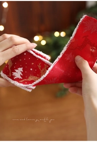Detailaufnahme von rotem Weihnachtsband mit weißem Kunstfellrand und Rentierdruck