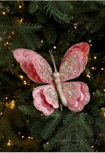 Nahaufnahme eines rosa Samt-Weihnachtsschmetterlings mit Goldpailletten am Baum