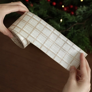 Champagne plaid Christmas ribbon roll with gold accents on festive dark wood background