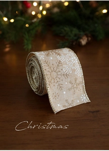 Dettaglio del nastro natalizio in lino beige con motivi a fiocchi di neve bianchi e oro