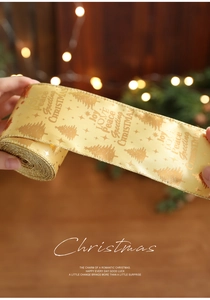 Macro view of gold Christmas ribbon with metallic tree patterns and festive greetings