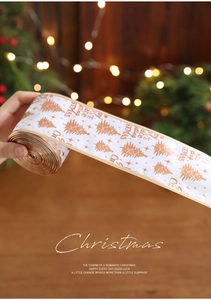 Close-up of white and gold Christmas ribbon with festive tree prints and holiday greetings