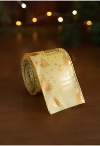 Detail of Christmas ribbon with gold foil trees and festive text on a warm bokeh backdrop