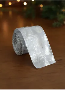 Detail of silver Christmas ribbon with gold tree prints and festive words on wood