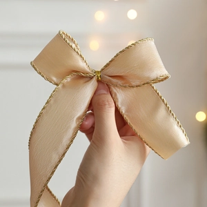 Champagne gold satin ribbon bow with metallic gold woven edges for gift wrapping decoration