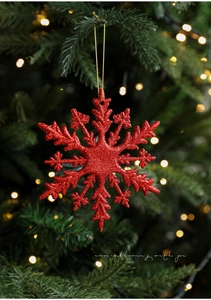 Nahaufnahme einer roten Glitzer-Schneeflocke mit goldener Schnur am Weihnachtsbaum