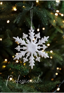 Nahaufnahme der weißen Glitzer-Schneeflocke am Weihnachtsbaum mit warmen Bokeh-Lichtern