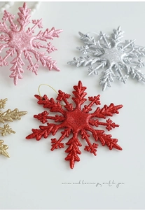 Detail von glitzernden Weihnachts-Schneeflocken in Rot, Rosa, Silber und Gold mit Kordel