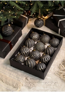 Close-up of 12 vintage black and gold Christmas ball ornaments with embossed textures in a box
