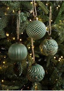 Detail of vintage green and gold Christmas ornaments hanging on a tree with warm lights