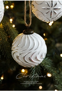 Close-up of 8cm white Christmas ball with silver spiral relief and twine on a tree