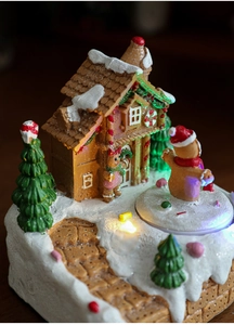 Close-up of glowing resin gingerbread house with LED lights and festive characters