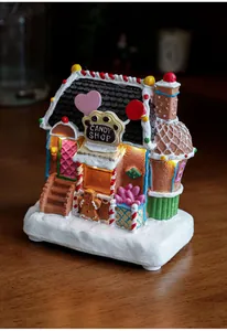 Close-up of lighted resin gingerbread candy shop with warm LED glow and snow base