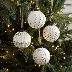 Set of four 8cm vintage white Christmas balls with gold embossing hanging on a tree
