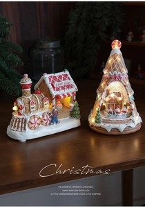 Close-up of lighted resin Christmas house with spinning music box and warm LED glow