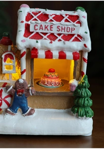 Detail of light-up resin Christmas gingerbread cake shop with snowy roof and warm LED glow