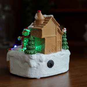 Luminous resin gingerbread house with snow-covered Christmas trees and LED lighting