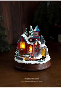 Détail d'une maison de Noël en résine avec train rotatif et lumières LED chaudes