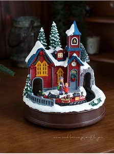 Détail du petit train de Noël rotatif autour d'un chalet rouge enneigé miniature