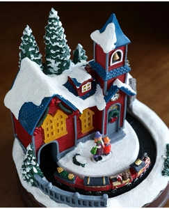 Détails macro d'un village de Noël lumineux avec train rotatif et maisons en résine enneigée