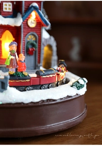 Détail de la maison de Noël lumineuse avec train rotatif et figurines sous la neige