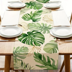 Detail of floral table runner with monstera leaves and gold line art on linen fabric
