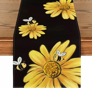 Close-up of floral table runner with sunflower and bee prints on black fabric texture