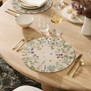 Close-up of linen round placemat featuring vibrant wildflower prints on a wooden table