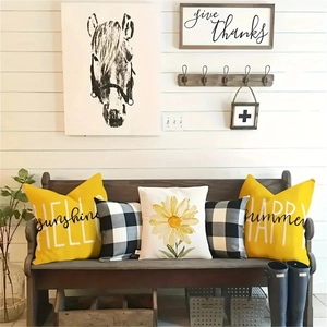 Five-piece yellow watercolor daisy and buffalo plaid decorative cushion covers on wooden bench