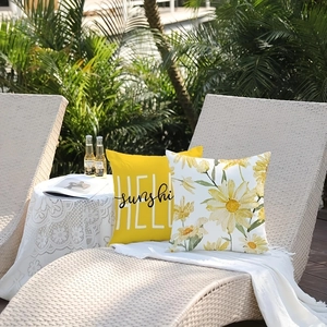 Detail of yellow HELLO sunshine and watercolor daisy throw pillow covers on a lounge chair