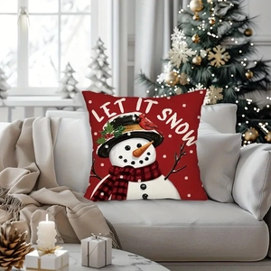 Close-up of Let It Snow snowman cushion cover on sofa near a decorated Christmas tree