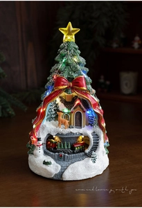 Détail de la maison de Noël lumineuse en résine avec train rotatif et renne miniature