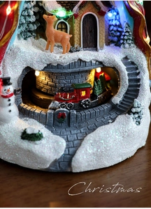 Détail d'une maison de Noël lumineuse avec un train rotatif et un petit cerf décoratif