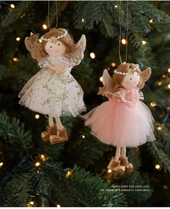 Detailed view of plush angel ornaments with deer antlers hanging on a lit Christmas tree