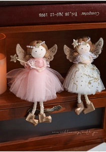 Macro detail of plush angel dolls with glitter tulle skirts and golden wings on wood