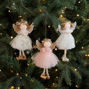 Three plush Christmas angel dolls with sequins and tulle wings hanging on a lighted tree