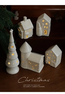 Detailed view of glowing white ceramic Christmas village house ornaments on wooden steps