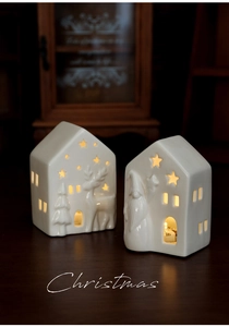 Detailed view of white ceramic glowing Christmas houses with warm light and star cutouts