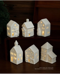 Detailed view of six miniature white ceramic Christmas houses with warm glowing LED windows