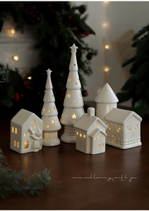 Detail of five-piece glowing ceramic Christmas village with warm LED lights and star cutouts