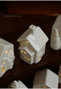 Ceramic Christmas house set with warm glowing LED lights on wooden stairs