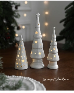 Three glowing white ceramic Christmas tree ornaments with star cutouts on wood