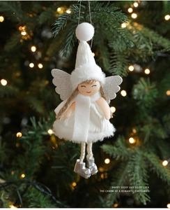 Close-up of white plush Christmas angel ornament with silver wings on tree branches
