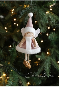 Close-up of pink Christmas angel plush ornament with golden boots on a tree