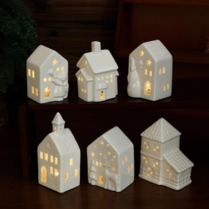Set of six white ceramic glowing Christmas houses with hollow designs and warm light