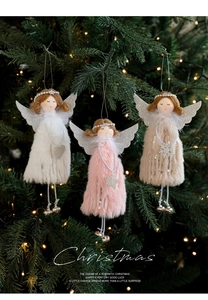 Three plush angel doll ornaments with silver wings and bells hanging on a lit Christmas tree