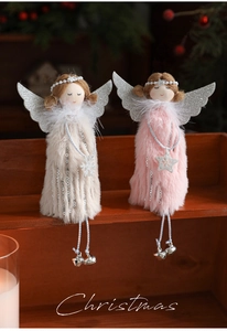 Close-up of plush angel ornaments with faux fur, silver wings, and bells on wood