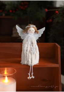Detail of plush Christmas angel doll with silver wings and bells on wooden shelf